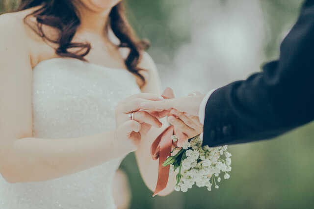 woman putting ring on man's finger at wedding