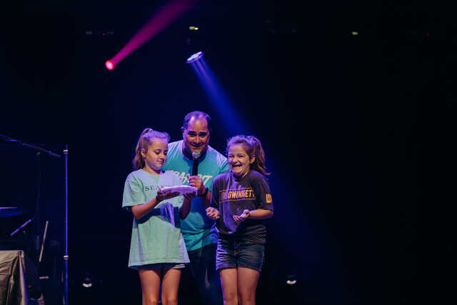 transit host on stage with two middle school girls