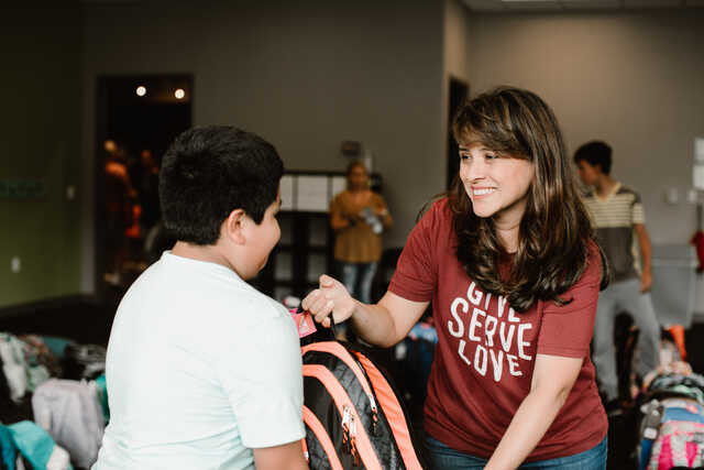 young boy giving a volunteer a backpack for the back to school drive
