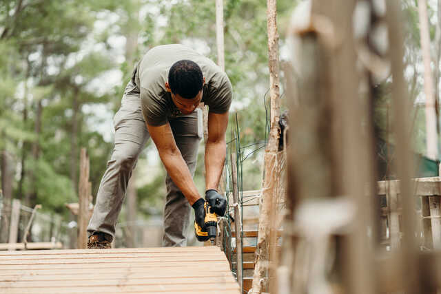 young man using a drill to build a wooden pathway